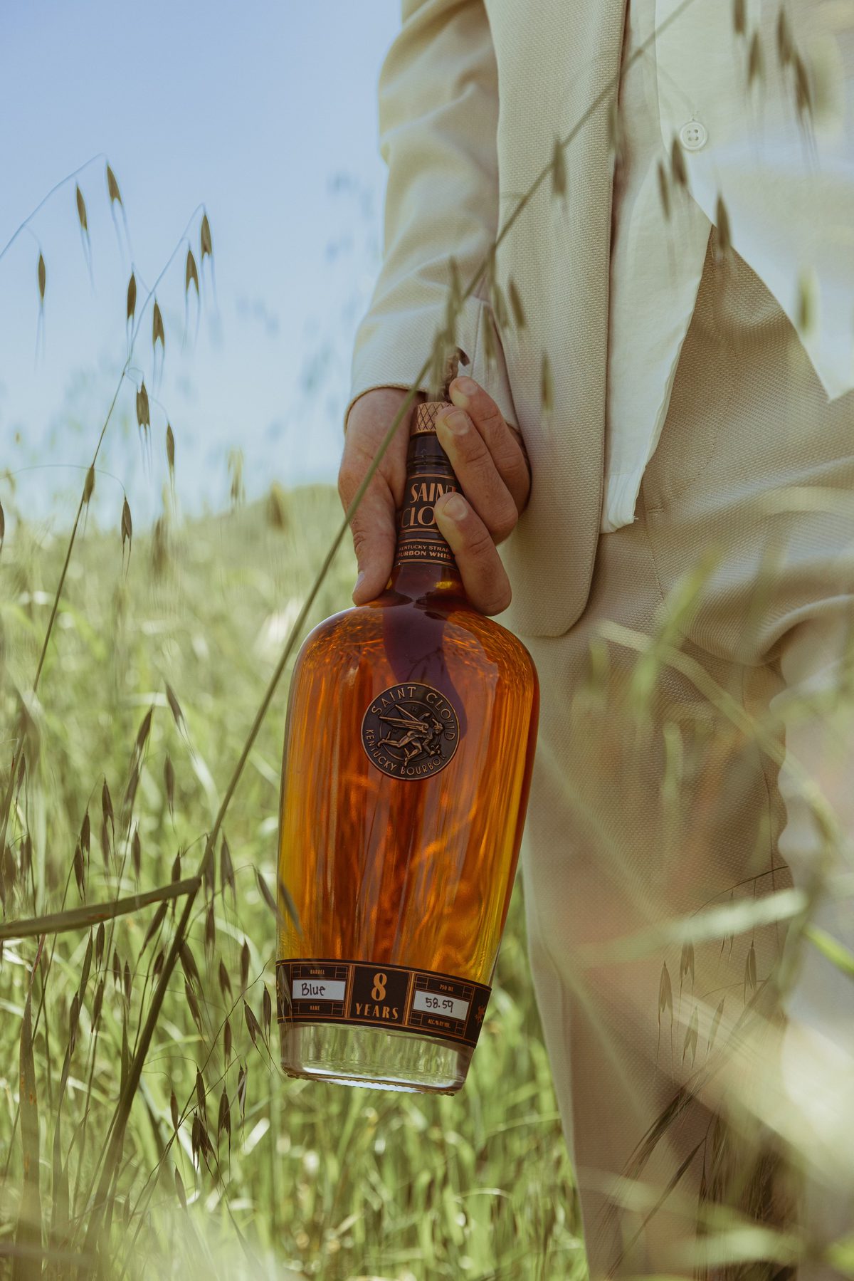 A bottle of Saint Cloud 8 Year held at the hip in a field of tall grass